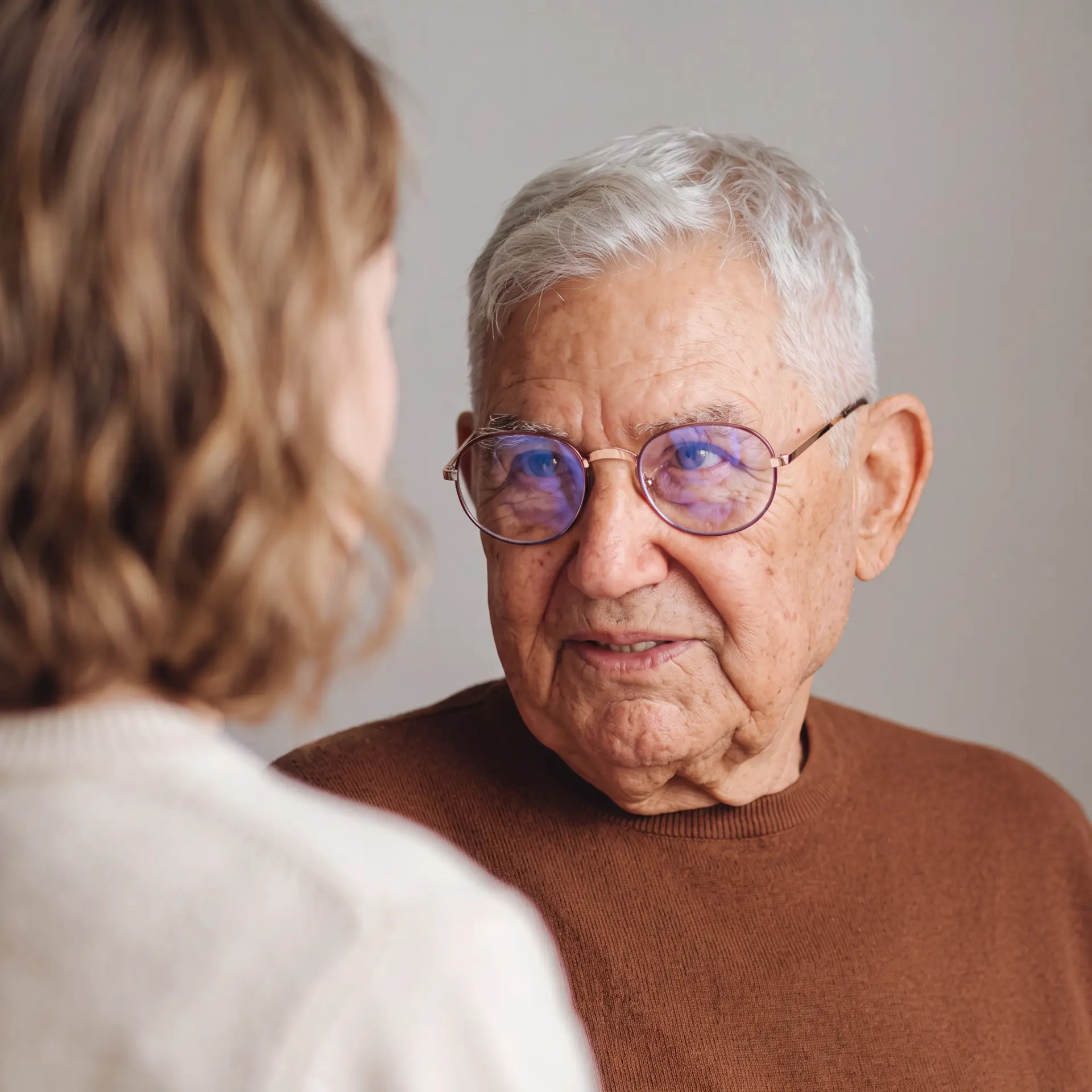 An adult daughter sitting with her elderly father at home